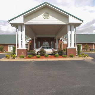 A covered building entrance with columns and surrounding landscaping.