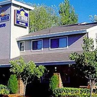 A hotel building with a visible sign and surrounding trees.