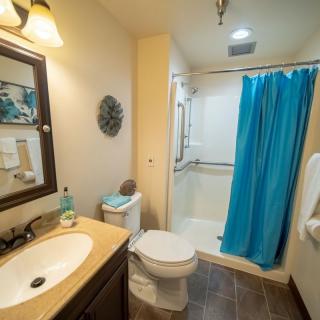A modern bathroom with a blue shower curtain and well-lit sink area.