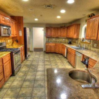 A spacious kitchen with wooden cabinets, tiled floor, and modern appliances.