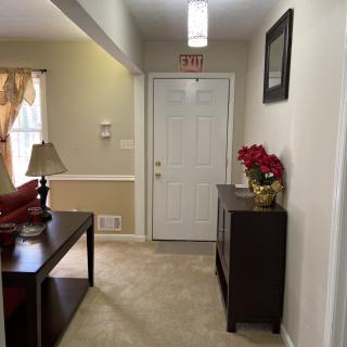 A cozy hallway with a table, lamp, and floral arrangement near the entrance.
