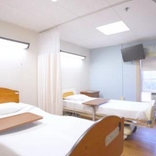 A clean and well-lit hospital room with two beds.
