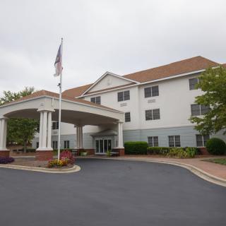 A hotel building with a covered entrance and an American flag in the foreground.