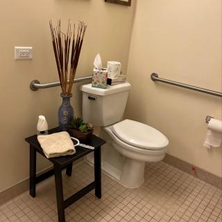 A well-decorated bathroom with a toilet, side table, and decorative items.