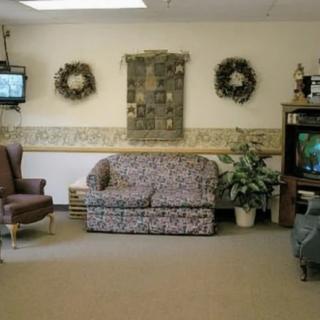 A cozy waiting room with a sofa and television, decorated with wreaths on the wall.