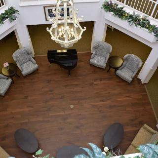 An elegant interior with a central grand piano surrounded by comfortable seating and a large chandelier overhead.