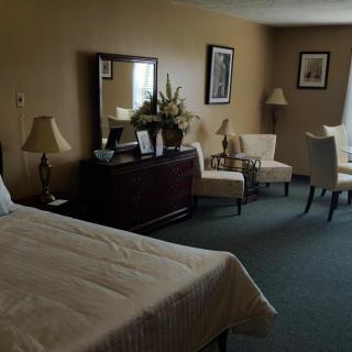 A cozy bedroom with a bed, dresser, and seating area.