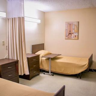 A hospital room with two patient beds and a curtain divider.