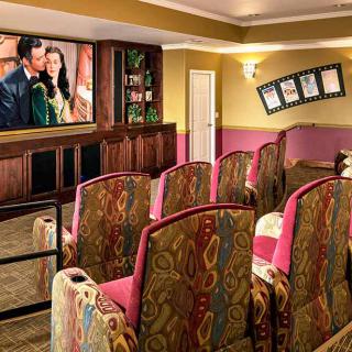 A cozy home theater setup with patterned seats and a large screen displaying a movie.