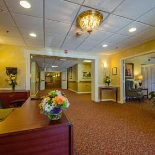 A well-decorated lobby area featuring a reception desk, floral arrangements, and a chandelier.