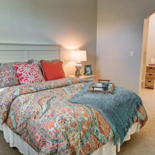A cozy bedroom with a well-decorated bed featuring colorful pillows and a patterned comforter.