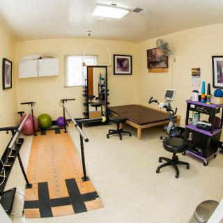 A well-equipped physical therapy room with exercise equipment and a therapy table.