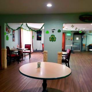 A cozy interior of a restaurant featuring green decorations and empty seating.
