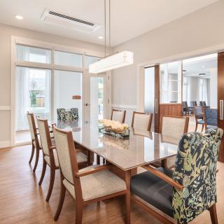 A modern dining room with a sleek table, upholstered chairs, and large glass doors allowing natural light to flood the space.