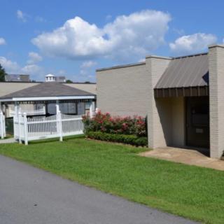 A small building with a well-maintained lawn under a blue sky with clouds.