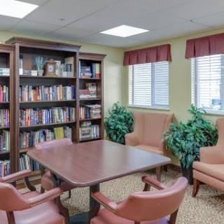 A cozy reading and meeting area featuring bookshelves, comfortable seating, and indoor plants.