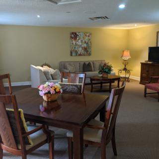 A cozy living room with a dining table, comfortable sofa, and a television setup.