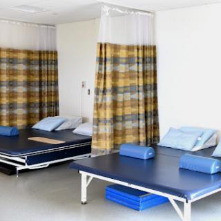 A quiet hospital room with beds separated by privacy curtains.