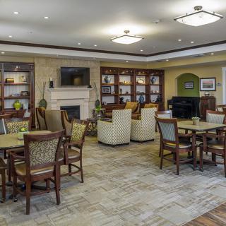 A cozy seating area with tables, chairs, bookshelves, a fireplace, and a television.