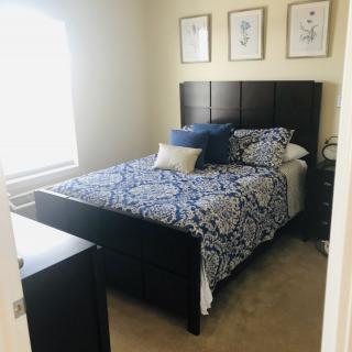 A cozy, well-decorated bedroom with a bed, pillows, and framed art on the wall.