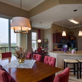 A modern dining area adjacent to a kitchen, featuring stylish lighting and comfortable seating.