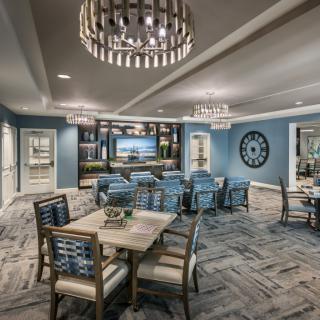 A modern dining room with elegant chandeliers, featuring blue walls and comfortable seating.