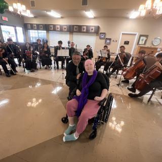 A joyful moment at a community musical performance, featuring an orchestra and attendees enjoying the show.