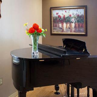 A grand piano with a vase of flowers on top, set in a stylish room with a painting on the wall.
