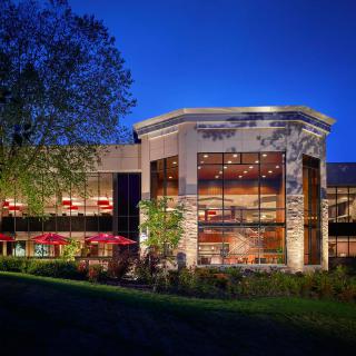 A beautifully lit building at night with surrounding trees and outdoor seating.