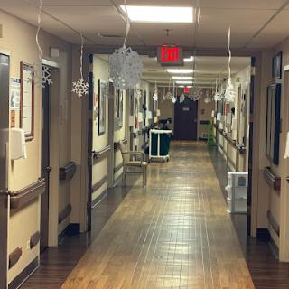 A decorated hospital hallway with snowflakes hanging from the ceiling.