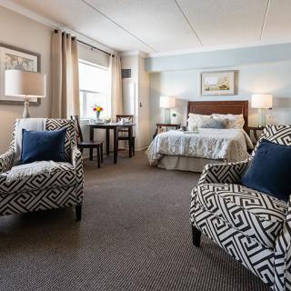A cozy bedroom with patterned chairs, a comfortable bed, and elegant decor.