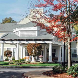A residential building with a columned entrance and autumn trees.