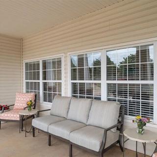 A cozy porch with comfortable outdoor seating and tables by the window.