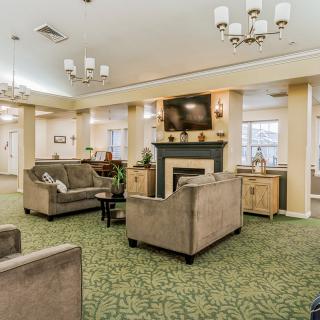 A cozy living room with sofas, a fireplace, and elegant chandeliers.