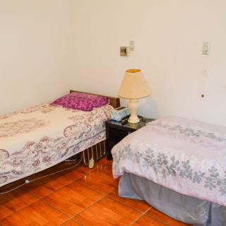 A cozy bedroom with two single beds, a nightstand, and a lamp.