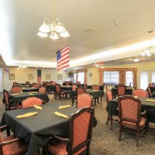 A spacious dining room with neatly arranged tables and chairs, featuring a hanging American flag.