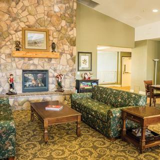 A cozy living room with a stone fireplace, patterned sofas, and a wooden coffee table.