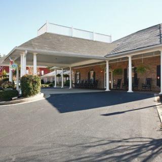 The image shows the exterior entrance of a hotel with a covered driveway and columns.