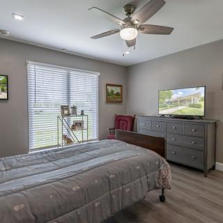 A cozy bedroom features a bed, dresser, and ceiling fan with natural light streaming through the window.