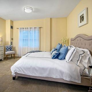 A cozy and modern bedroom featuring a neatly made bed with blue accent pillows, soft lighting, and tasteful decor.