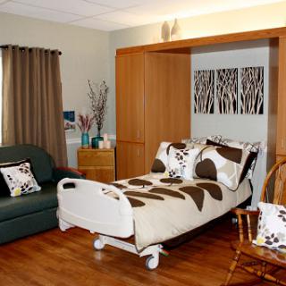 A cozy and well-decorated hospital patient room featuring a medical bed, comfortable seating, and tasteful decor.