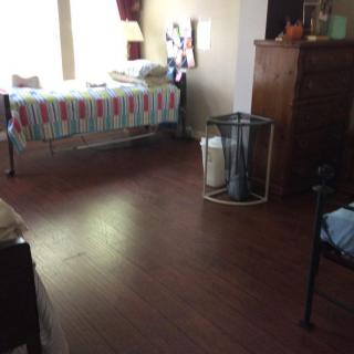 A tidy bedroom with a neatly made bed and wooden floors.
