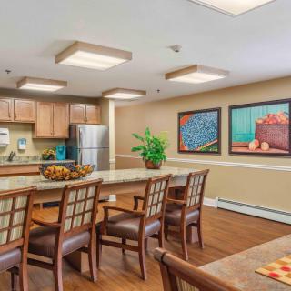 A modern kitchen and dining area featuring a large table with chairs, wooden cabinetry, stainless steel appliances, and decorative artwork on the walls.