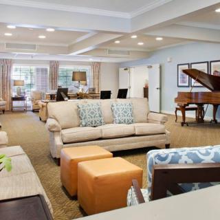 A spacious and elegantly decorated living room featuring comfortable sofas and a grand piano.