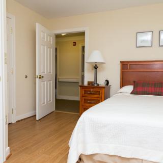 A cozy bedroom with a neatly made bed, wooden furniture, and warm lighting.