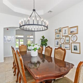 Elegant dining room featuring a long wooden table, stylish chairs, and a modern chandelier.