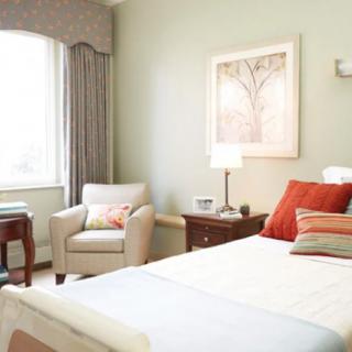A cozy and modern bedroom with elegant decor, featuring a comfortable bed, a stylish chair by the window, and a bedside lamp.