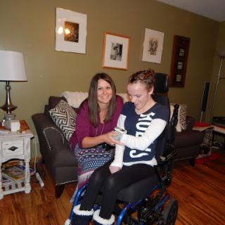 A caregiver assists a young woman in a wheelchair, highlighting a moment of support and companionship.