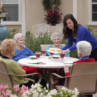 A group of senior women enjoying a meal together outdoors.