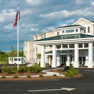 A hotel's entrance with an American flag and landscaped surroundings.